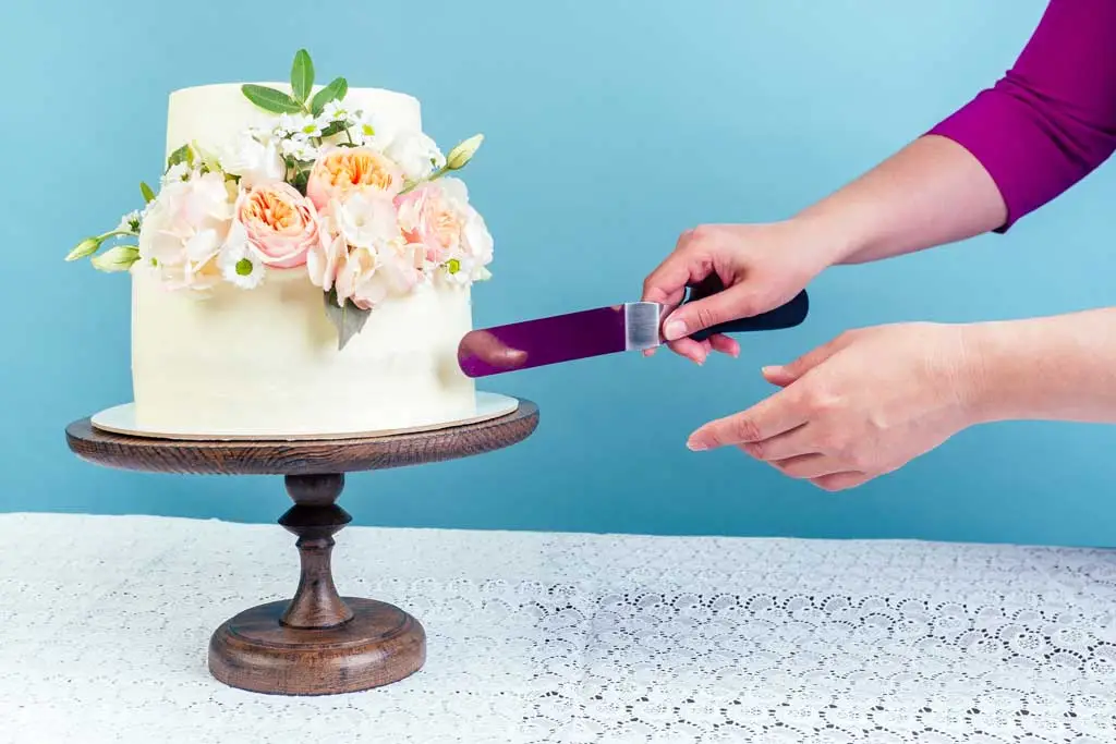 hands cutting floral wedding cake