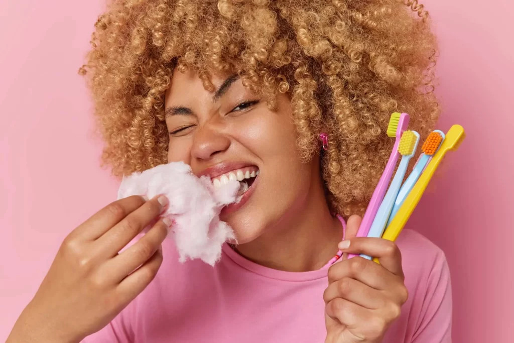 woman holds toothbrushes and cotton candy 2159146811