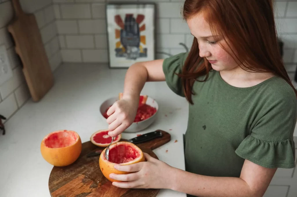 young girl scooping grapefruit offset 840157