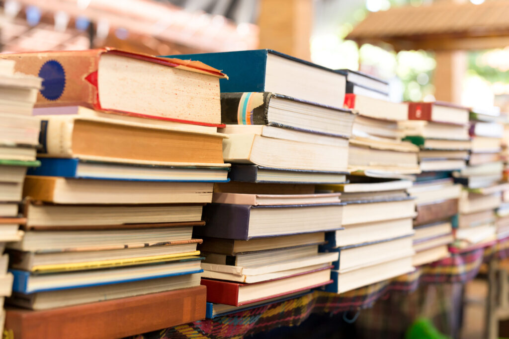 Piles,Of,Old,Books,On,A,Table,In,Blur,Background