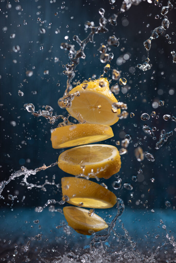 Splash,Of,Sliced,Lemon,With,Water,Drops,Over,Blue,Background