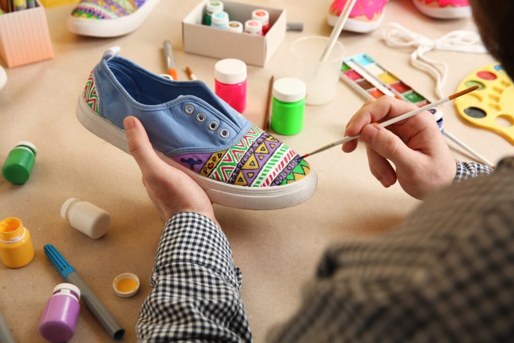 Man,Painting,On,Sneaker,At,Table,,Closeup.,Customized,Shoes